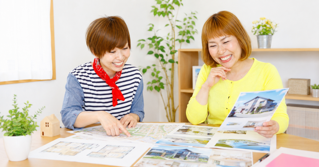 ドラとゴッチが高知市の不動産購入について、物件資料を見ながら相談している様子